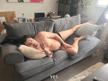 a shirtless man is laying on a couch with the word yes written below him