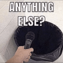 a person holding a microphone in front of a trash can with the words anything else written on it