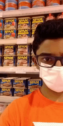 a man wearing a mask stands in front of a shelf full of spam cans