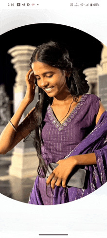 a woman in a purple dress is smiling and holding her hand to her face