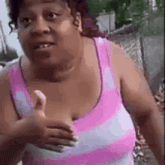 a woman in a pink and purple striped tank top is giving a thumbs up sign .