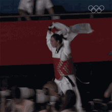 a person is holding a flag over their head in front of a sign that says ' olympics ' on it