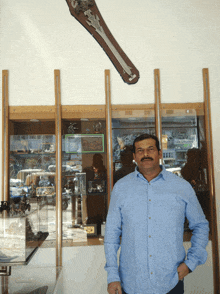 a man in a blue shirt is standing in front of a display case