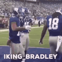 a group of football players are standing on a field and one of them is wearing a jersey with the number 18 on it .