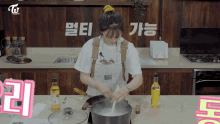 a woman in an apron stirs something in a pot in a kitchen with korean writing on the wall behind her