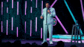 a man in a suit is standing on a stage holding a microphone