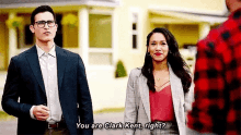 a man and a woman are standing in front of a house and talking to each other .