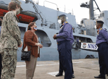 a group of people standing in front of a ship that says nns on it