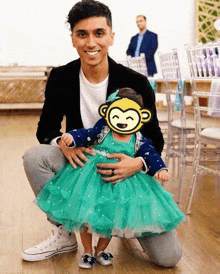 a man is kneeling down with a little girl in a green dress with a yellow monkey covering her face