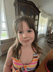 a little girl wearing a colorful striped top smiles for the camera