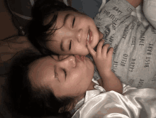 a woman is kissing a child who is wearing a shirt that says " best baby "