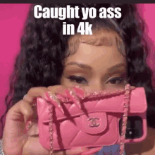 a woman with long nails is holding a pink chanel purse .