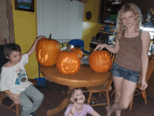 a boy wearing a shirt that says paw patrol stands next to a girl holding a pumpkin