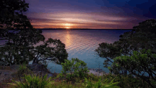 a sunset over a lake with trees in the foreground