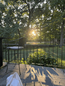 a chair sits on a patio with the sun shining through the trees behind it