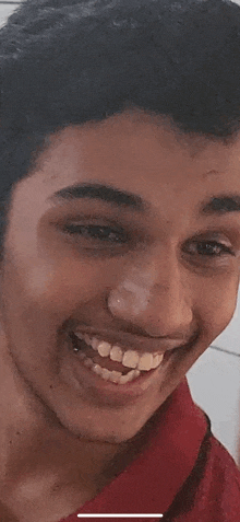 a close up of a young man 's face with a nose ring and a red shirt .