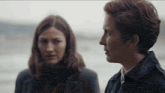 two women are standing next to each other and looking at each other .
