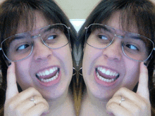 a woman wearing glasses and a ring is smiling in a mirror