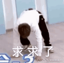 a man is bending over on the floor with chinese writing on the floor .