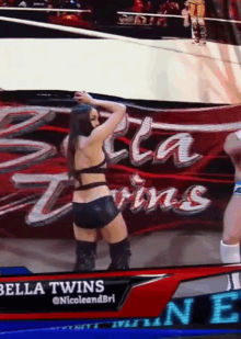 a woman is dancing in front of a banner that says bella twins on it