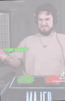 a man with a beard and headphones is playing a video game with green and red buttons .