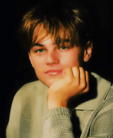 a close up of a young man 's face with his hand resting on his chin