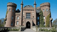 a large brick castle with a lot of towers and a bridge in front of it .