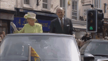 queen elizabeth ii and prince philip in a car in front of a sign that says ' a l '