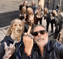 a group of zombies are posing for a picture with a man wearing sunglasses giving the middle finger