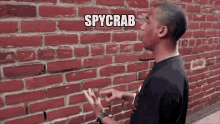 a man standing in front of a red brick wall with the word spycrab on it