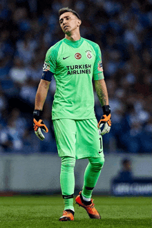 a soccer player wears a green shirt with turkish airlines on it