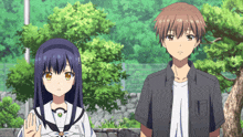 a boy and a girl are standing next to each other with trees in the background