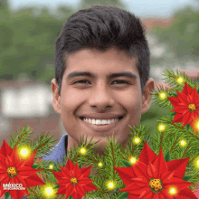 a young man is smiling in front of a christmas tree and poinsettia