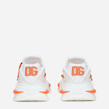 a pair of white shoes with orange dg letters on them