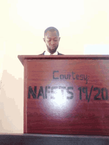 a man stands behind a podium that says courtesy nafsts 19/20