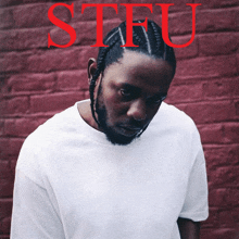 a man in a white shirt is standing in front of a red brick wall with the word stfu written in red