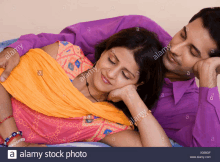 a man and a woman are laying on a bed and the woman is sleeping on the man 's lap