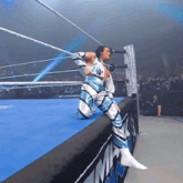 a wrestler is kneeling on the edge of a wrestling ring in front of a sign that says nm