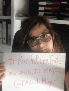 a woman wearing glasses holds up a sign that says #porunbuentrato