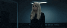 a woman stands in a dark room with a sign that says " rule at all times " on it