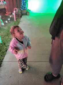 a little girl standing in front of a green candy cane