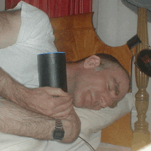 a man laying on a bed holding a small black object