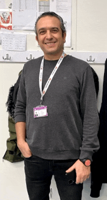 a man wearing a lanyard with a name tag that says ' a ' on it smiles for the camera