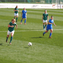 a group of female soccer players are playing on a field with a sign that says " football for all "