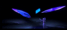 a woman is dancing in a dark room with purple and blue lights behind her