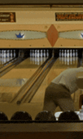 a man is playing bowling in a bowling alley with a sign that says ' bowling alley ' on it