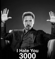 a man in a suit is sitting in a chair with his hands up and the words i hate you 3000 below him