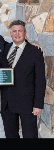 a man in a suit and tie is holding a framed picture .