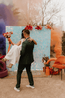 a bride and groom are dancing in front of a blue and orange backdrop