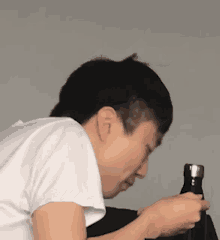 a man in a white shirt is drinking from a bottle